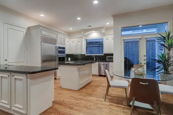 a kitchen with kitchen island granite countertop wooden floors and white cabinets