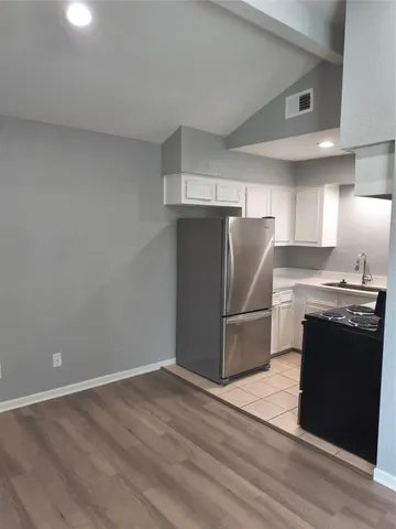 a kitchen with granite countertop a refrigerator and a stove top oven