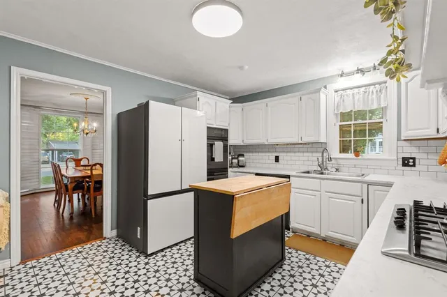 a kitchen with granite countertop a refrigerator a stove a sink a dining table and chairs