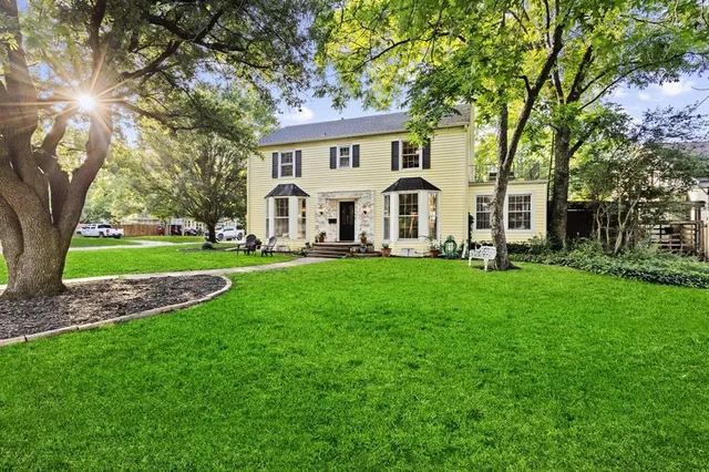 a front view of a house with a garden and trees