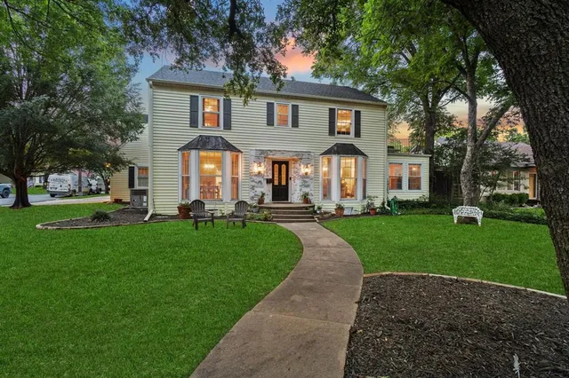 a front view of a house with a garden and trees