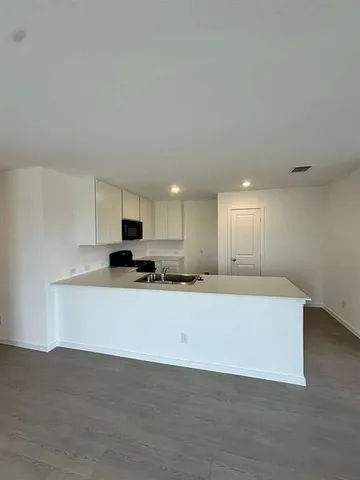 a living room with stainless steel appliances kitchen island sink and cabinets