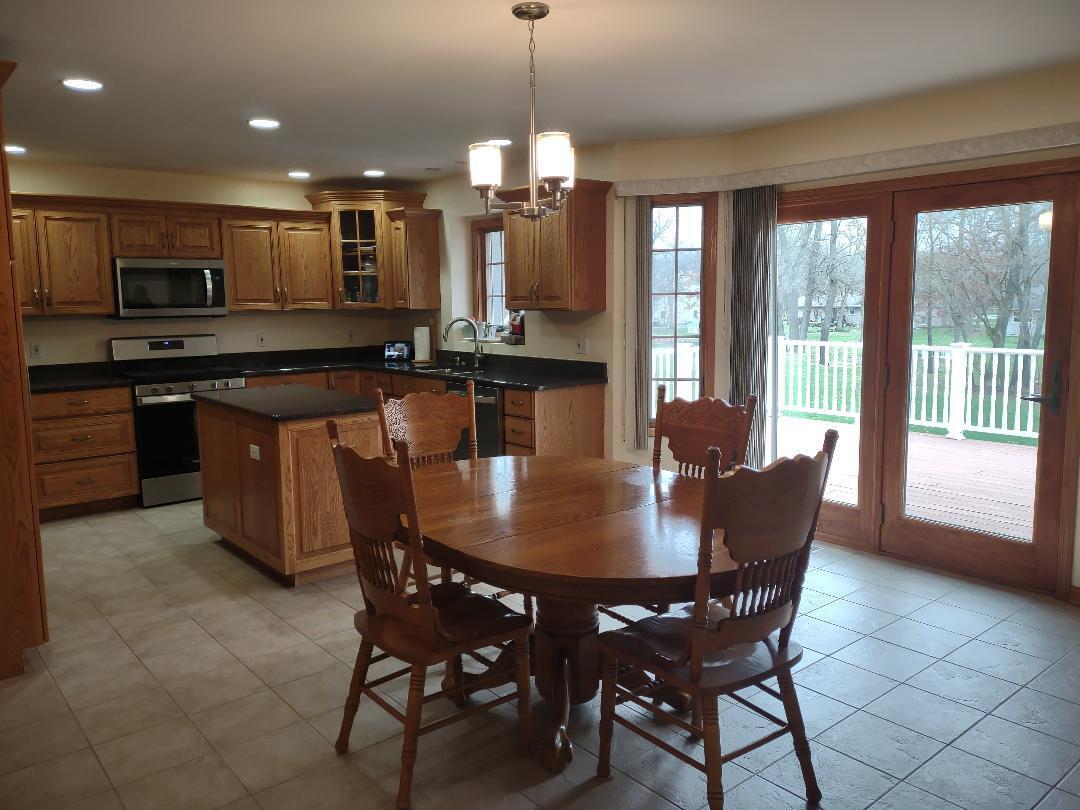 9800 Crestwood Circle Demotte, IN 46310 - Photo 6 of 25 a kitchen with a dining table chairs and stove