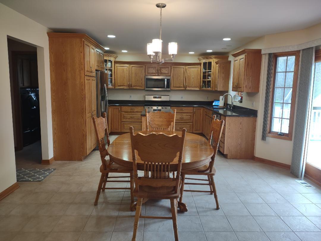 9800 Crestwood Circle Demotte, IN 46310 - Photo 7 of 25 a kitchen with a table chairs refrigerator and microwave