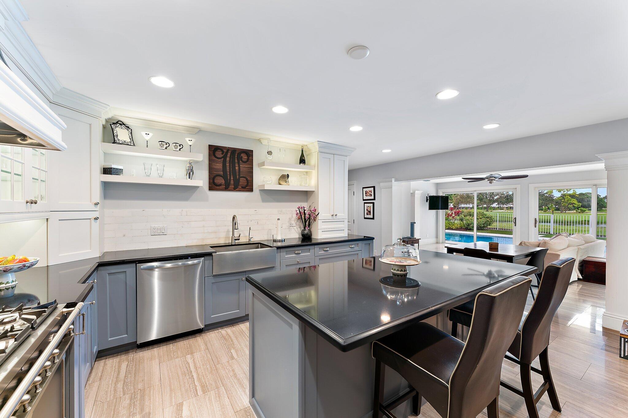 210 Golfview Drive Tequesta, FL 33469 - Photo 9 of 27 a kitchen with stainless steel appliances granite countertop a stove a sink a microwave a dining table and chairs