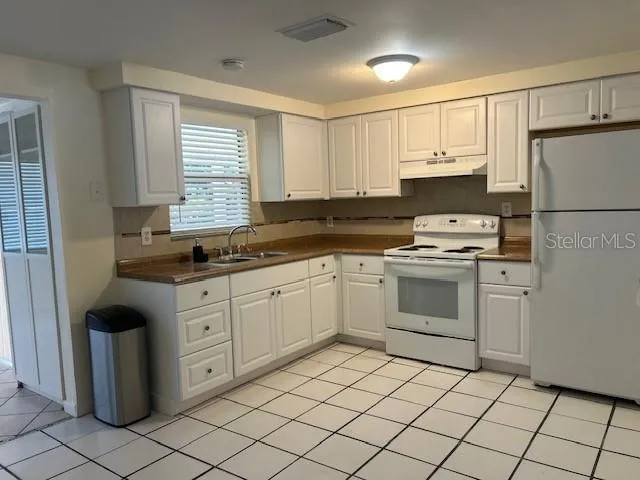 a kitchen with white cabinets appliances and a sink