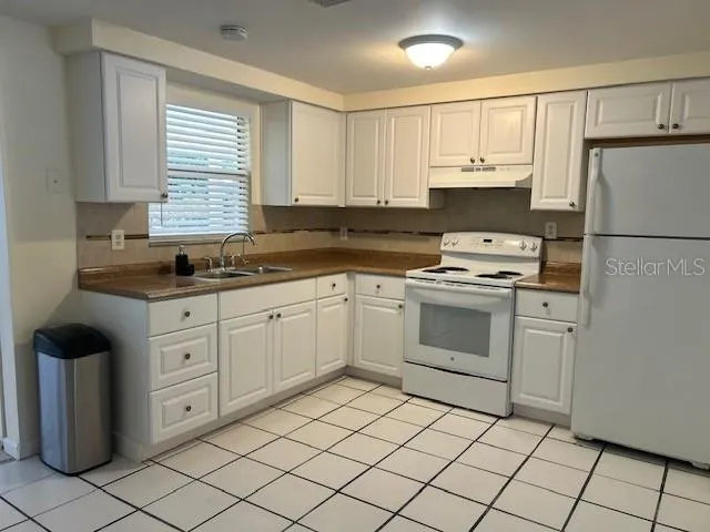 a kitchen with white cabinets appliances a sink and a counter top space