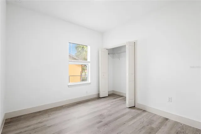 an empty room with wooden floor and window