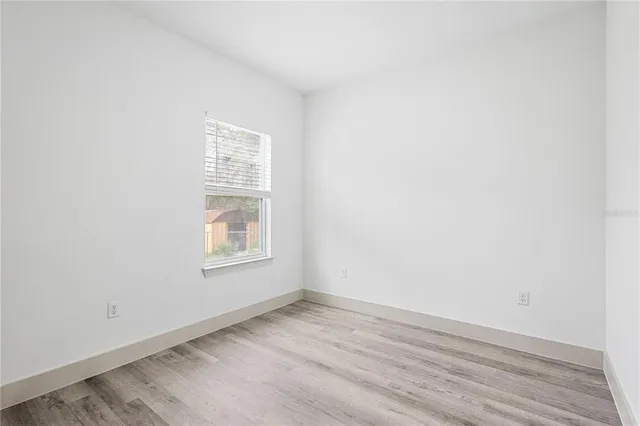 an empty room with wooden floor and window