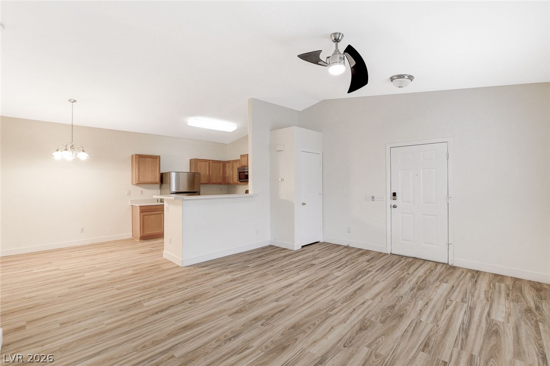 2052 Quarry Ridge Street, Unit 201 Las Vegas, NV 89117 - Photo 3 of 25 Laminate flooring flows throughout the open living area, connecting to a functional kitchen with warm wood cabinetry.