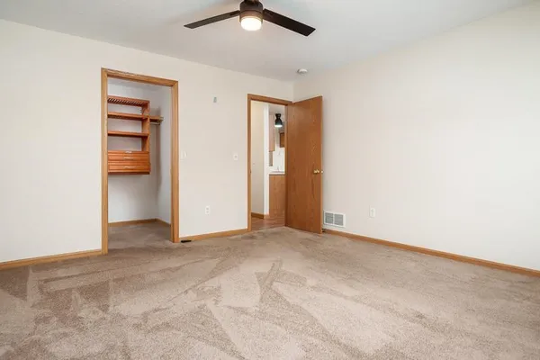 an empty room with closet and a ceiling fan
