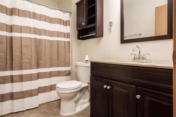 a bathroom with a sink a toilet a mirror and shower curtain