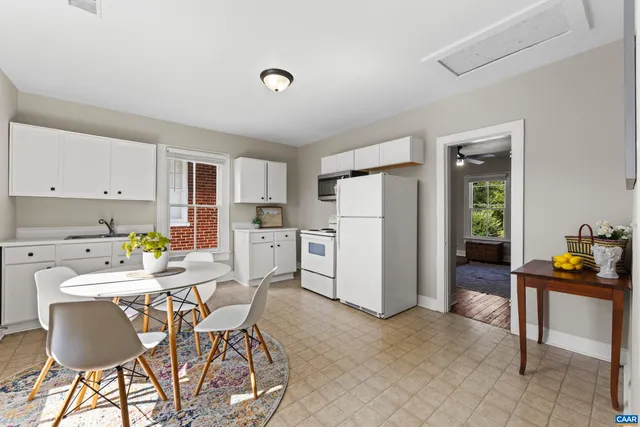 a dining room filled a chandelier and kitchen view