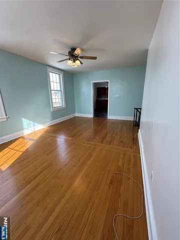 a view of empty room with wooden floor and fan
