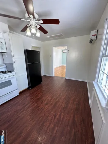 a view of an empty room with wooden floor and a ceiling fan
