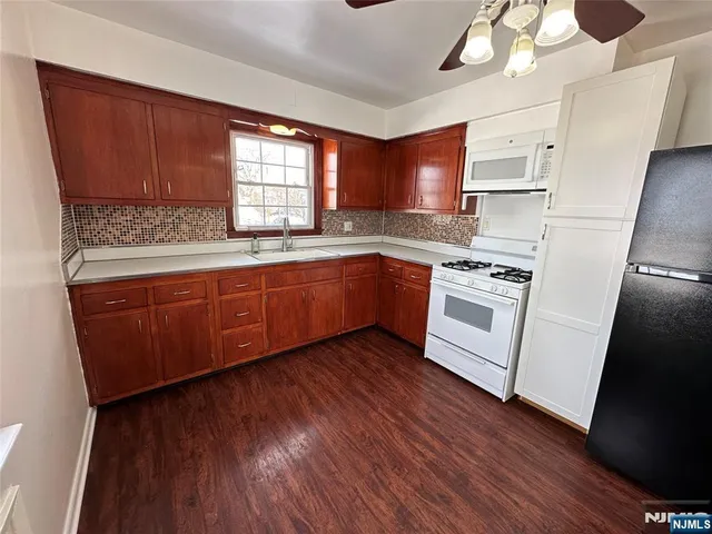 a kitchen with wooden floors and white stainless steel appliances