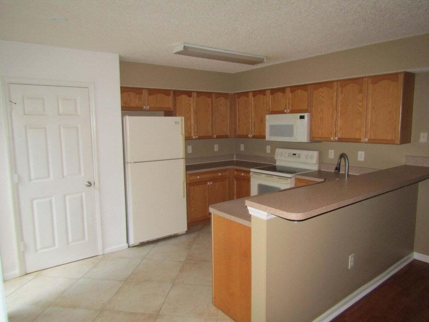 2212 White Pine Circle, Unit B Greenacres, FL 33415 - Photo 4 of 9 a kitchen with a sink a refrigerator and a stove