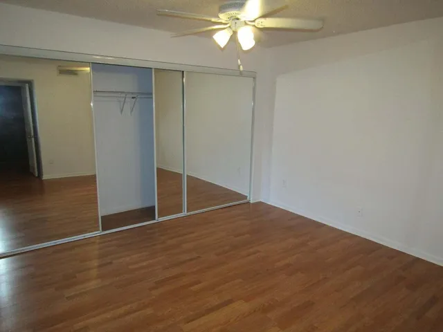 an empty room with wooden floor and fan