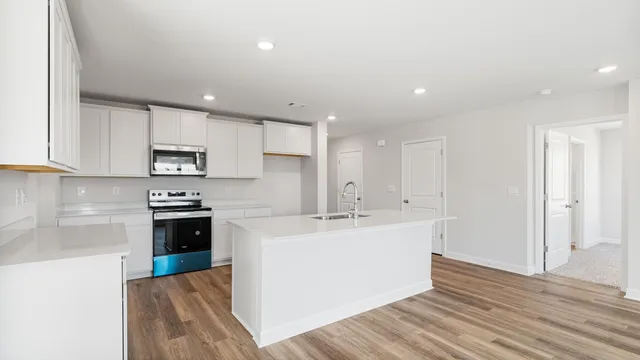 a kitchen with stainless steel appliances granite countertop a sink a stove a refrigerator a white cabinets with wooden floor