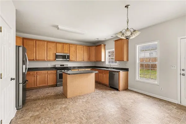 a kitchen with stainless steel appliances granite countertop a stove a sink dishwasher a refrigerator and a granite counter tops with white cabinets