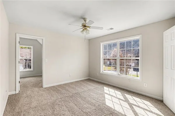an empty room with windows and fan