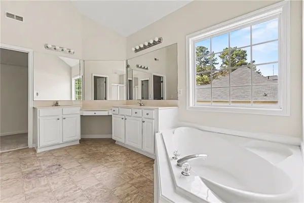 a bathroom with a tub sink a window and a mirror