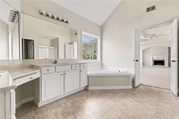 a spacious bathroom with a tub sink and mirror