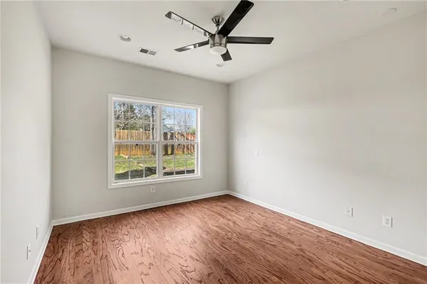 an empty room with wooden floor and windows