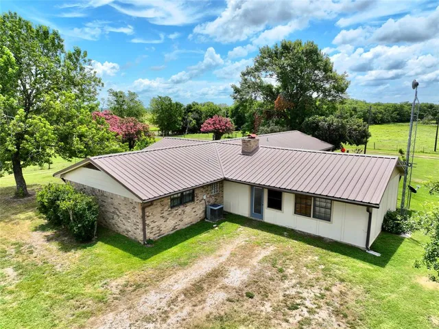 a view of a house with a yard plants and large tree