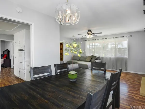 a view of a dining room with furniture a chandelier and wooden floor