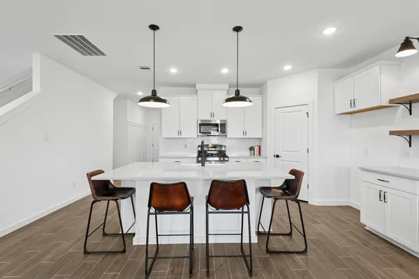 a kitchen with stainless steel appliances a dining table chairs stove and sink