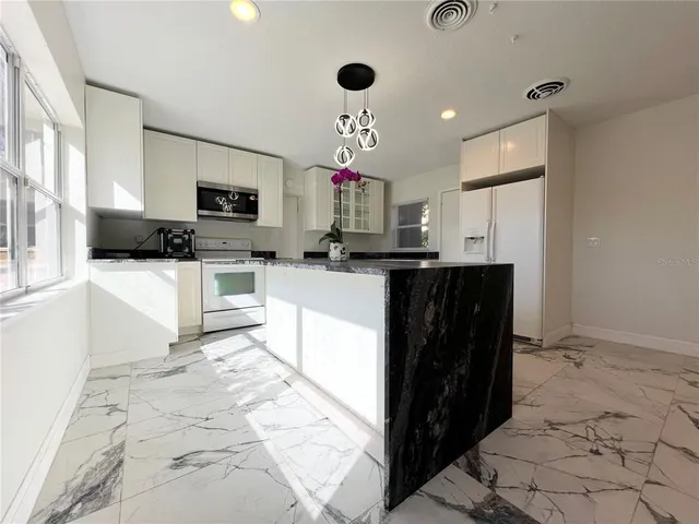 a kitchen with granite countertop a sink a counter top space appliances and cabinets