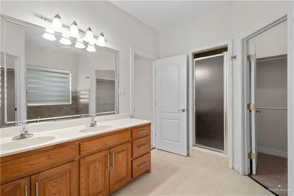 a bathroom with double vanity sinks a vanity a lamp and a mirror