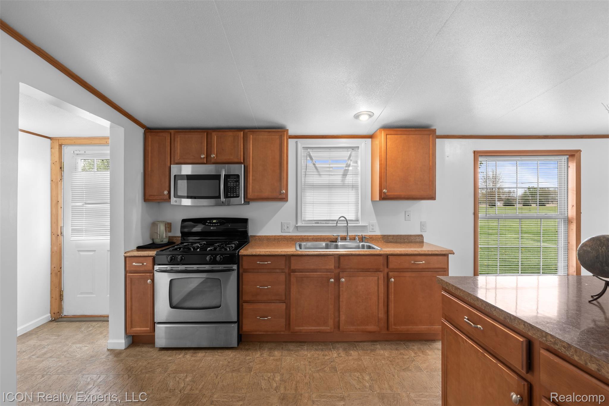 13620 Gilbert Road Allenton, MI 48002 - Photo 8 of 47 Kitchen with stainless steel appliances, wood finish cabinetry, ornamental molding, and dark stone countertops