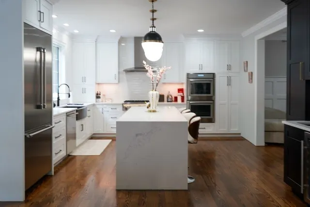 a large kitchen with kitchen island a large counter top stainless steel appliances and cabinets