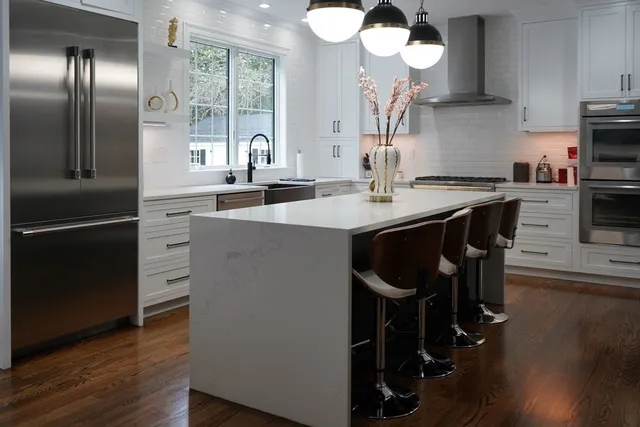 a kitchen with stainless steel appliances granite countertop a sink a stove and a wooden floors