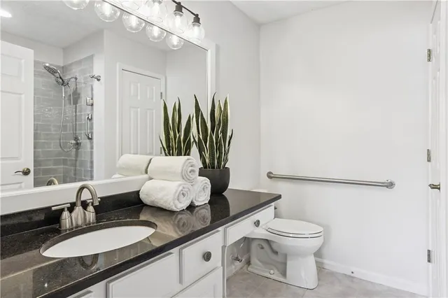 a bathroom with a granite countertop sink a toilet and mirror