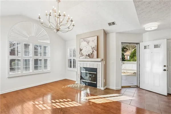 a view of a livingroom with a fireplace a chandelier and wooden floor