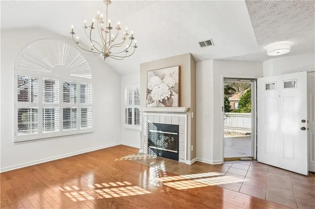 a view of a livingroom with a fireplace a chandelier and wooden floor