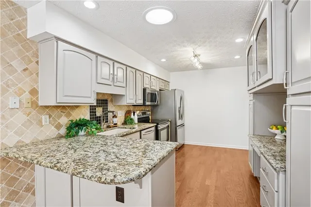 a kitchen with stainless steel appliances granite countertop a sink refrigerator and cabinets