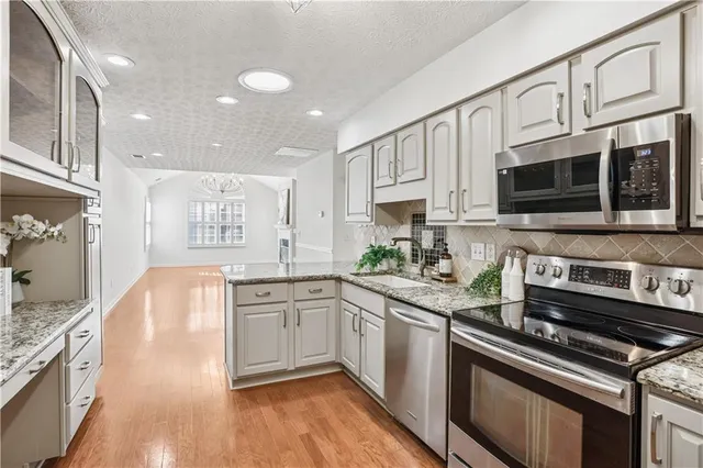 a kitchen with stainless steel appliances granite countertop a stove top oven a sink dishwasher a dining table and chairs with wooden floor