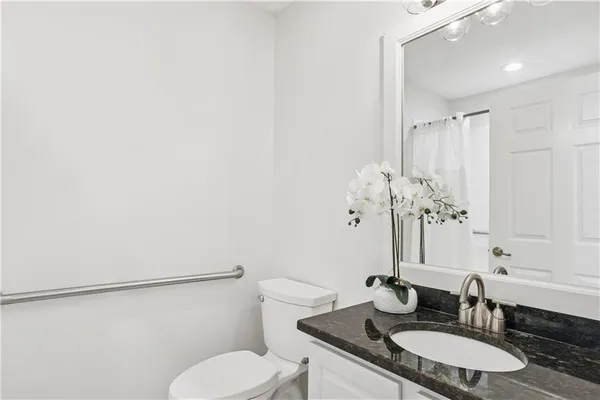 a bathroom with a granite countertop sink toilet and a mirror