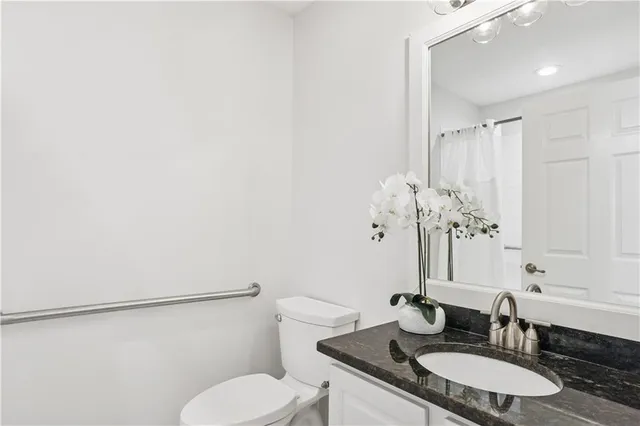 a bathroom with a granite countertop sink toilet and a mirror
