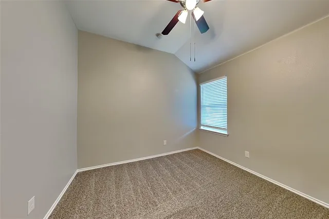 an empty room with a chandelier fan and windows