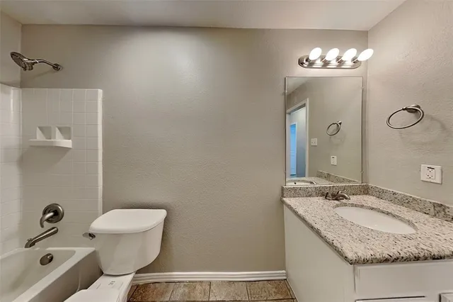 a bathroom with a granite countertop sink a toilet and mirror