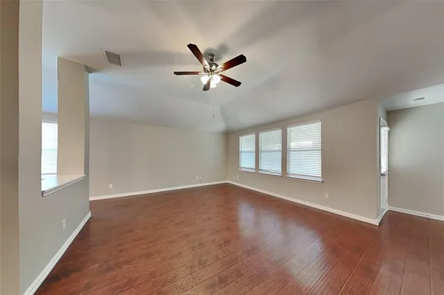 a view of an empty room with a window and wooden floor