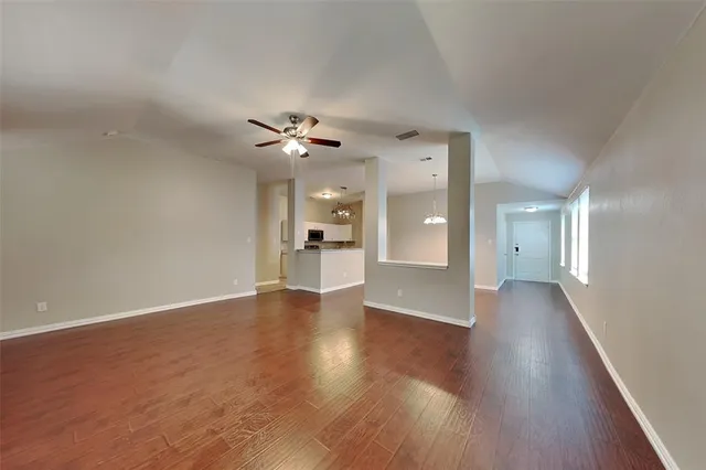 a view of a hallway with wooden floor and a kitchen