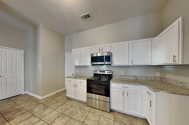 a kitchen with stainless steel appliances granite countertop a stove a sink and white cabinets