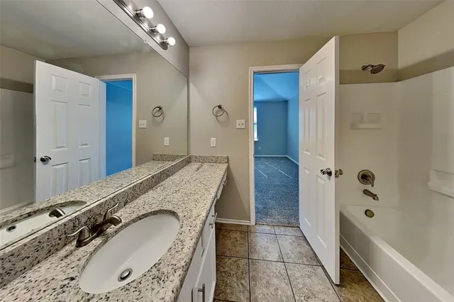 a bathroom with a granite countertop double vanity sink a mirror and a shower
