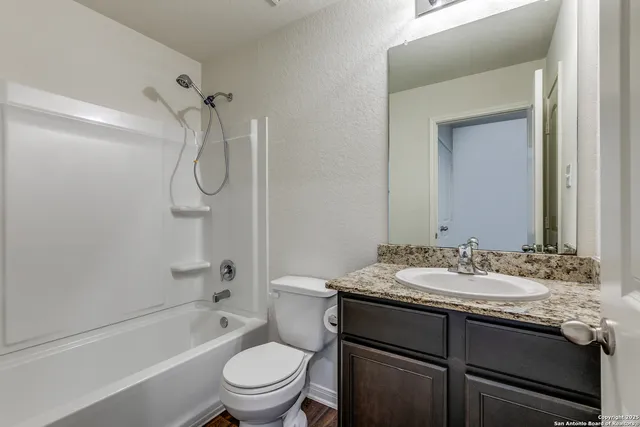 a bathroom with a granite countertop sink toilet vanity mirror and bathtub